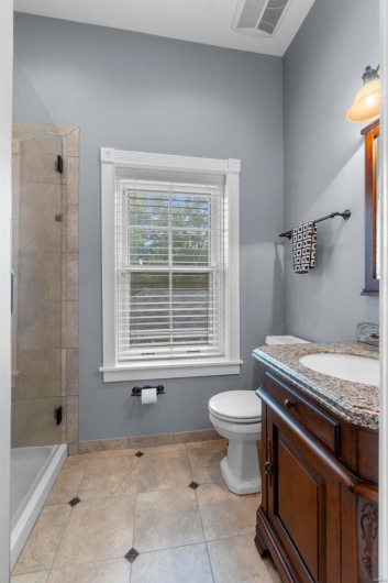 Bathroom featuring vanity, tiled shower, tile patterned floors, and toilet