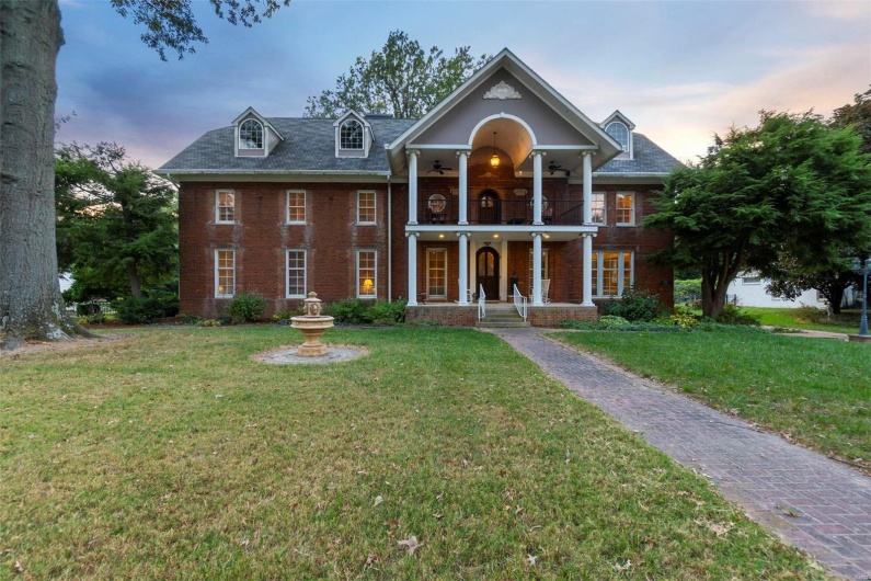 View of front of property featuring a balcony, a yard, and a porch
