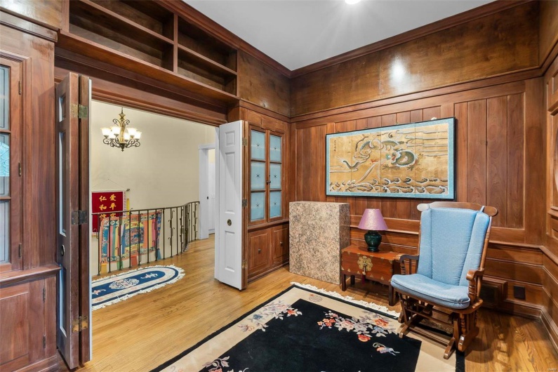 Sitting room with a chandelier, wooden walls, and light hardwood / wood-style floors
