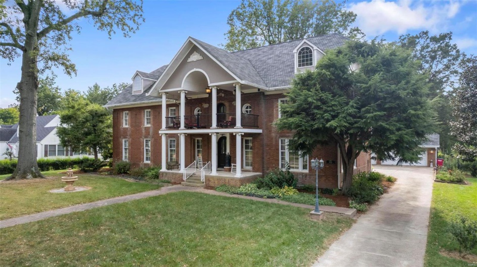 View of front of property with a balcony and a front lawn