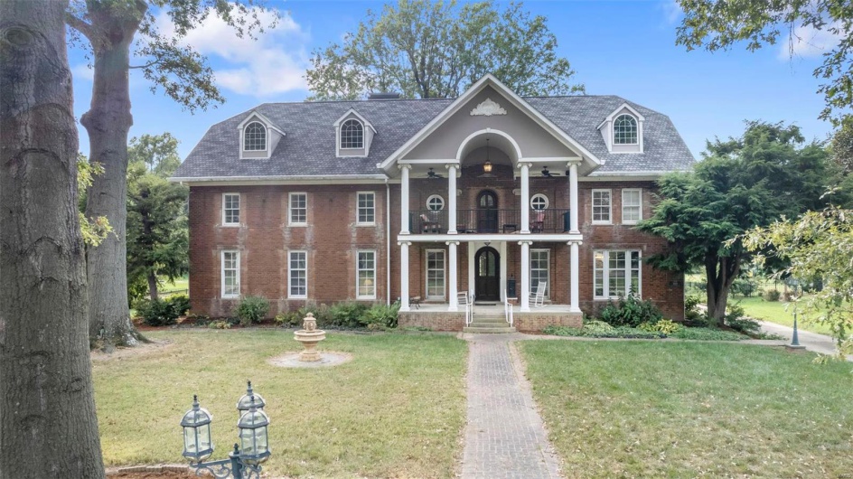 View of front of property with a balcony and a front yard