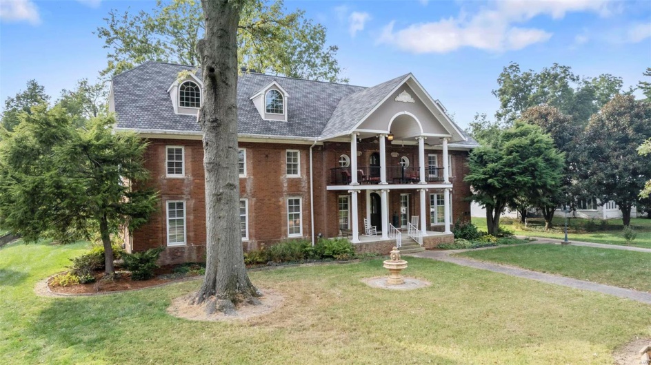 View of front of home with a front yard and a balcony