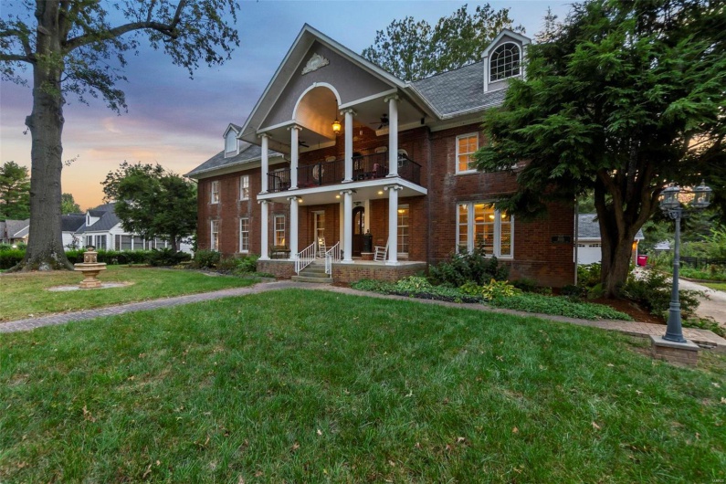 View of front facade with a balcony and a lawn