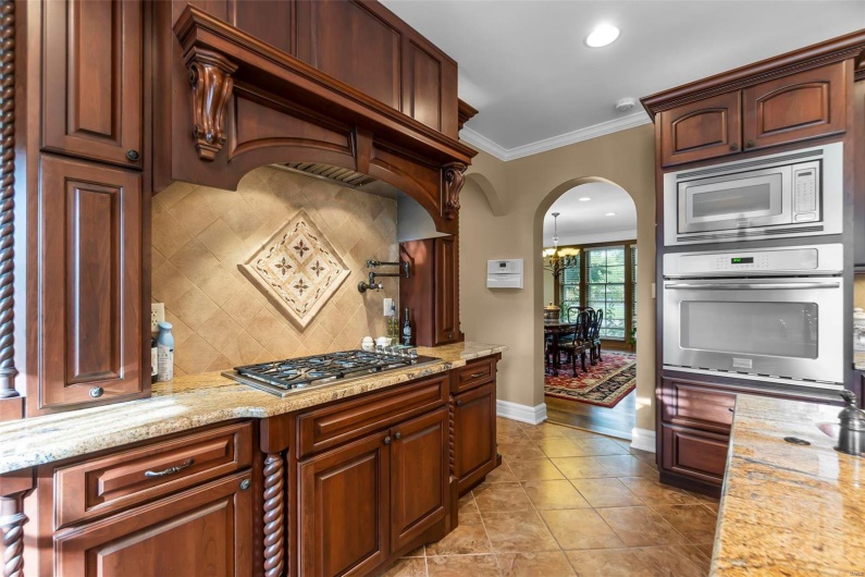 Kitchen with stainless steel appliances, ornamental molding, light stone countertops, and decorative backsplash
