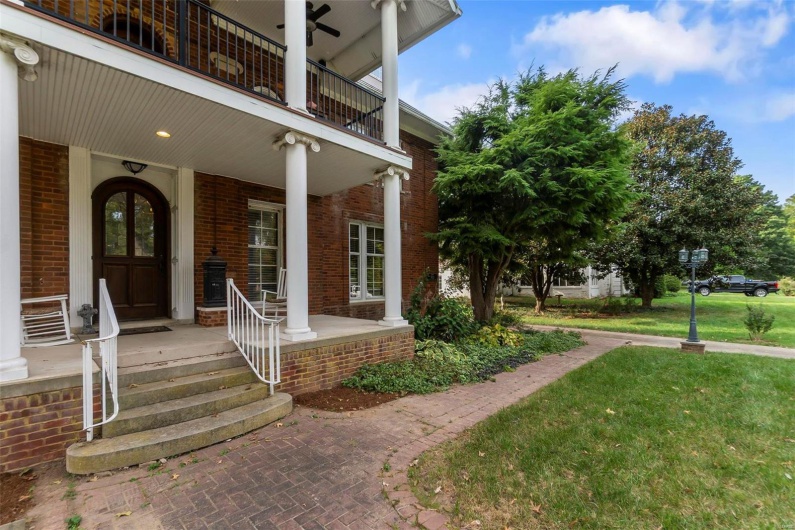 Entrance to property featuring a lawn, a balcony, and covered porch