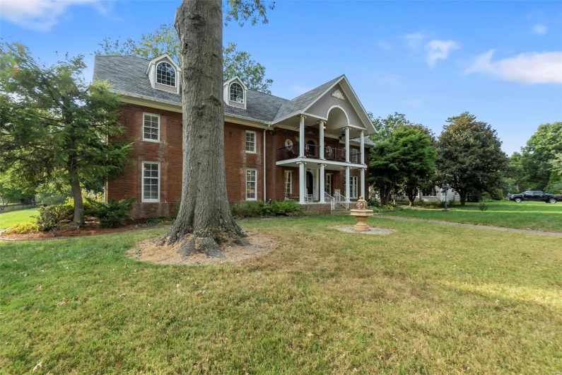 View of front facade with a front lawn and a balcony