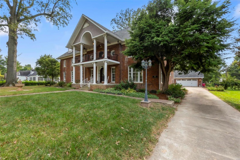 Greek revival house with a front lawn and a balcony