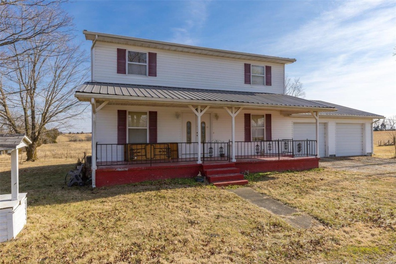View of front of house featuring a garage, a front yard, and covered porch
