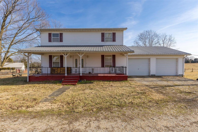 Farmhouse-style home with a garage, covered porch, and a front yard