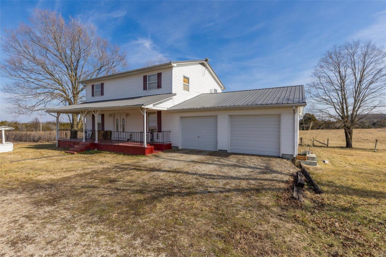 View of front of property featuring a porch, a garage, and a front lawn