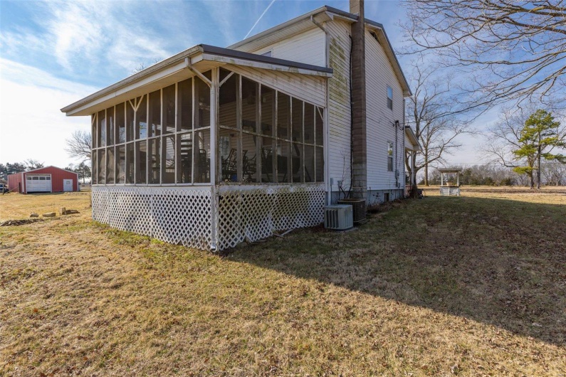 View of side of home featuring central AC, a sunroom, and a lawn