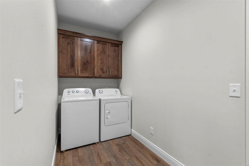 Laundry room with washing machine and dryer, cabinets, and hardwood / wood-style floors