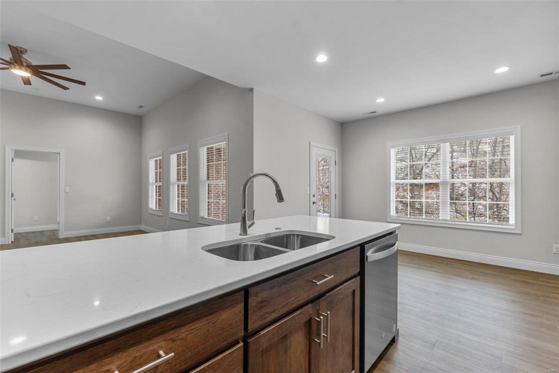 Kitchen featuring sink, light wood-type flooring, ceiling fan, stainless steel dishwasher, and dark brown cabinetry