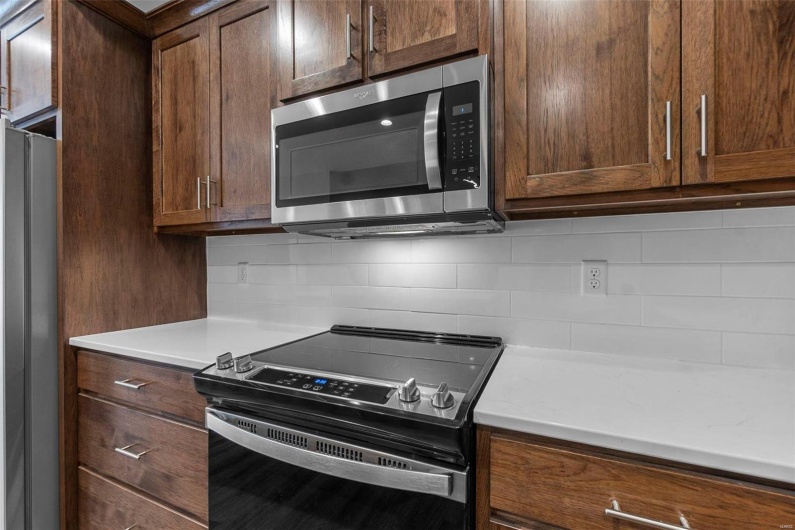 Kitchen with appliances with stainless steel finishes and decorative backsplash