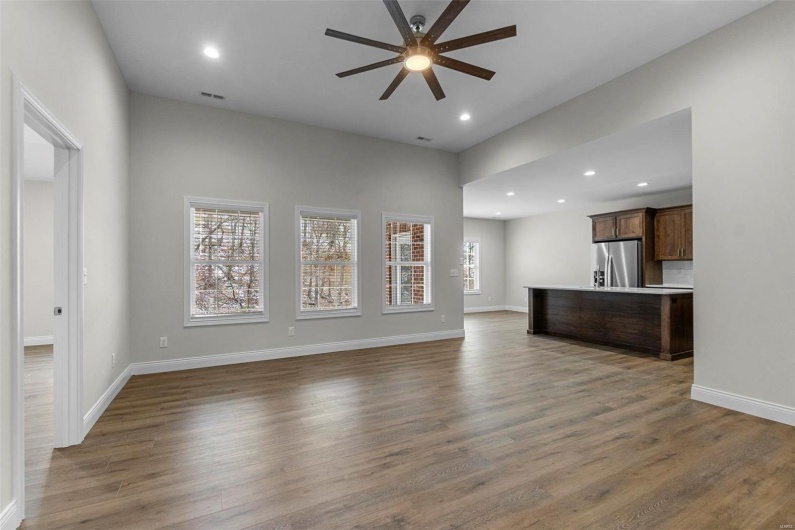 Unfurnished living room with a wealth of natural light, ceiling fan, and dark hardwood / wood-style floors