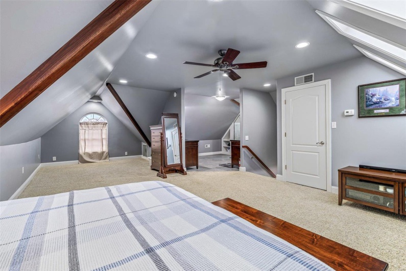 Carpeted bedroom featuring lofted ceiling with skylight