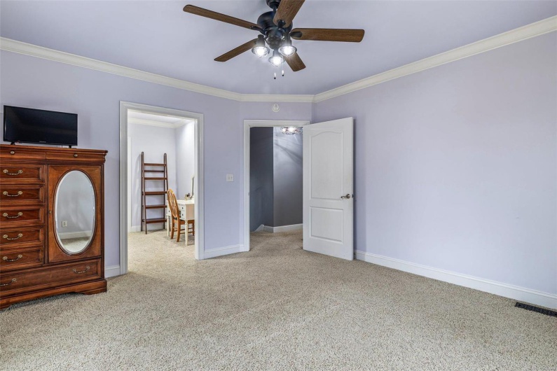 Unfurnished bedroom with crown molding, light colored carpet, and ceiling fan