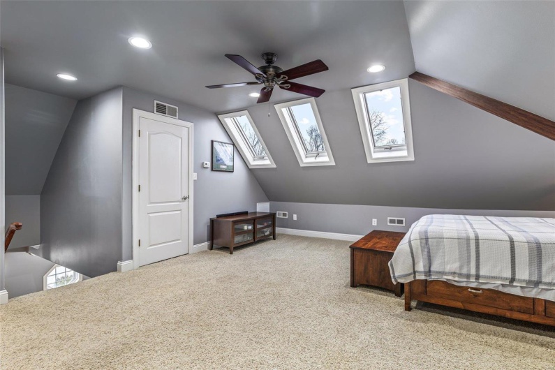 Bedroom featuring lofted ceiling with skylight, carpet, and ceiling fan