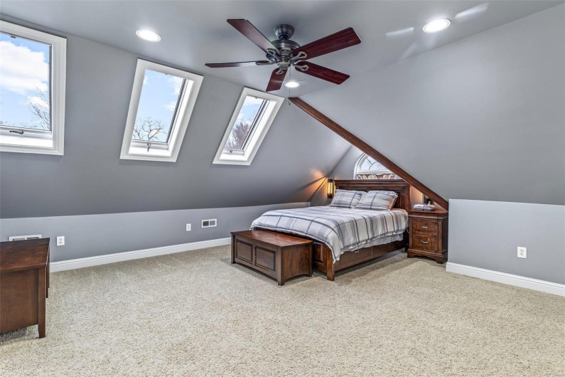 Bedroom with ceiling fan, multiple windows, vaulted ceiling, and light carpet