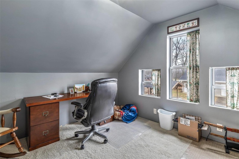 Carpeted office space featuring lofted ceiling