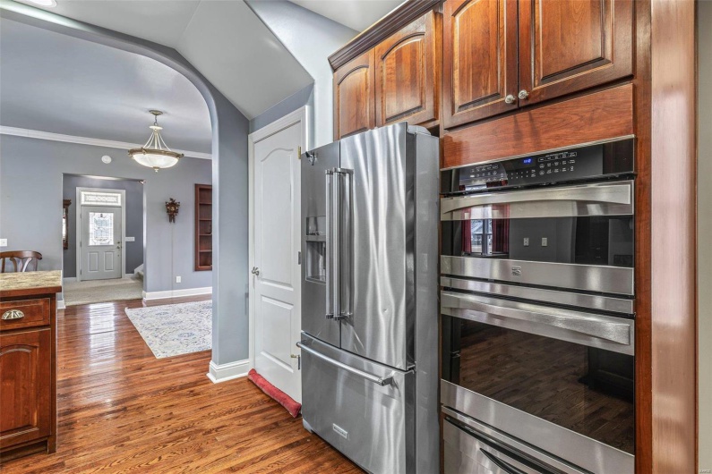 Kitchen featuring crown molding, dark wood-type flooring, stainless steel appliances, and vaulted ceiling