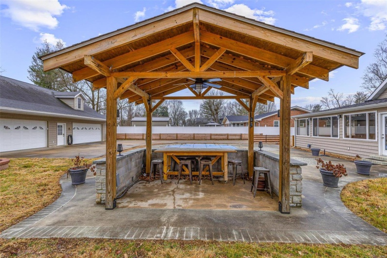 View of patio / terrace with a garage, ceiling fan, and exterior bar
