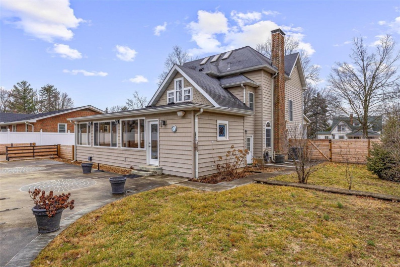 Rear view of house with central AC unit, a patio area, and a lawn