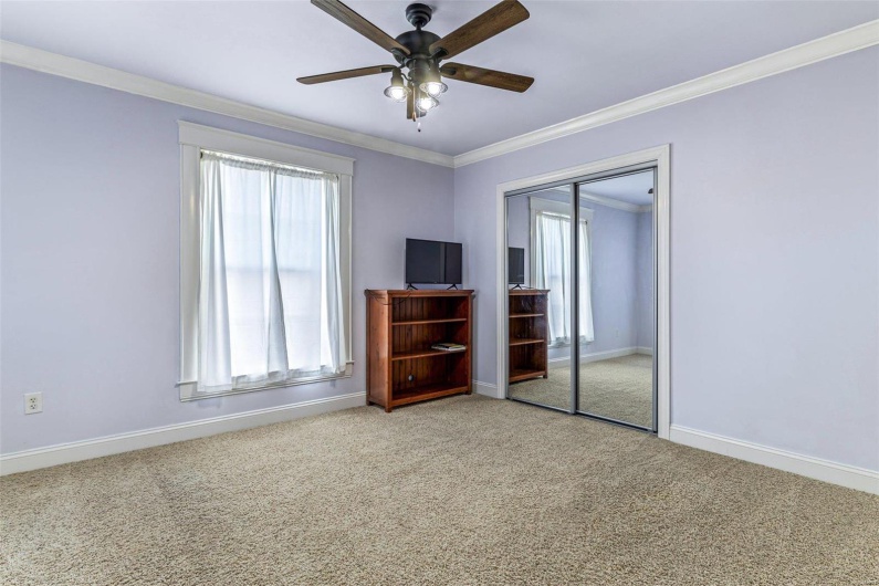 Unfurnished bedroom with ornamental molding, carpet floors, ceiling fan, and a closet