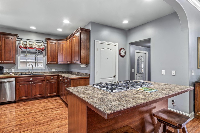 Kitchen with sink, a breakfast bar area, light stone counters, stainless steel appliances, and light hardwood / wood-style flooring