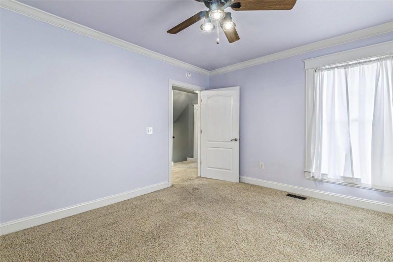 Empty room featuring ceiling fan, light colored carpet, and ornamental molding