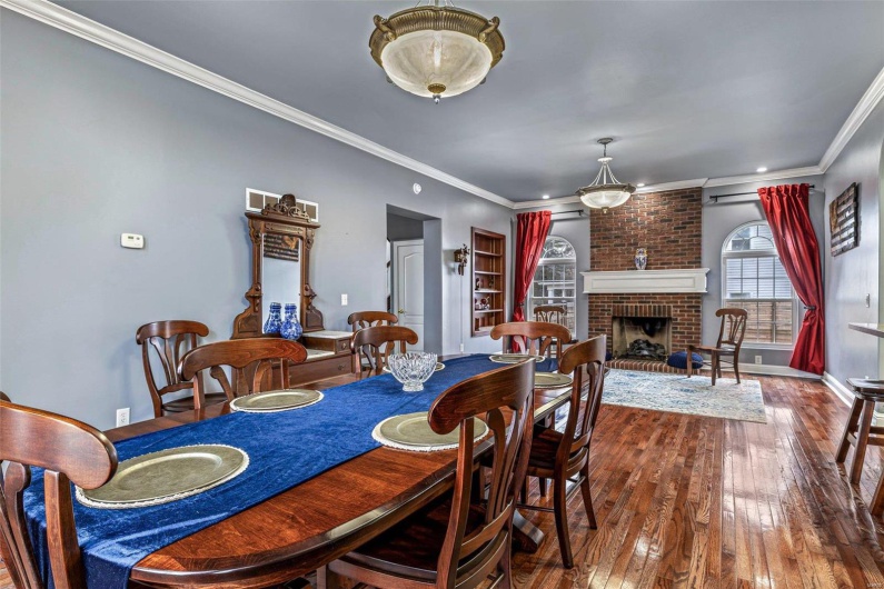 Dining room with a fireplace, wood-type flooring, and ornamental molding