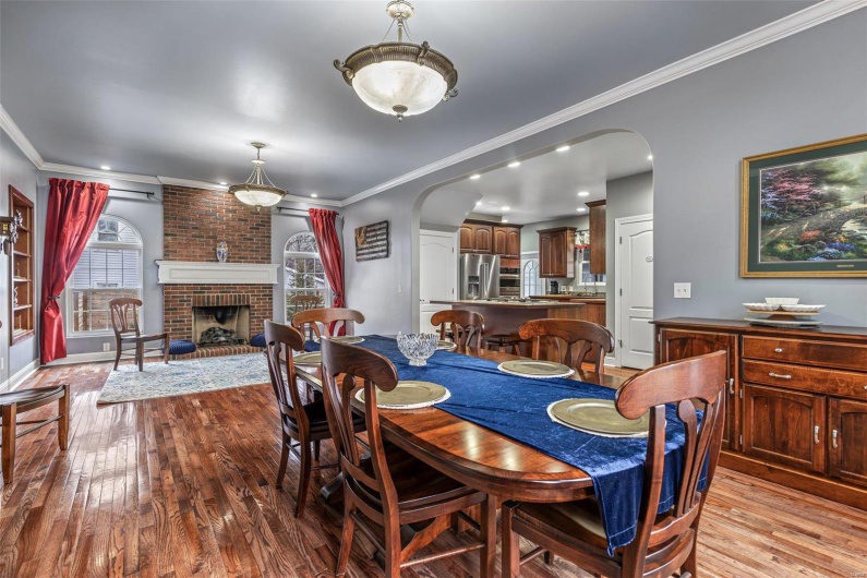 Dining room with crown molding, a fireplace, and light wood-type flooring