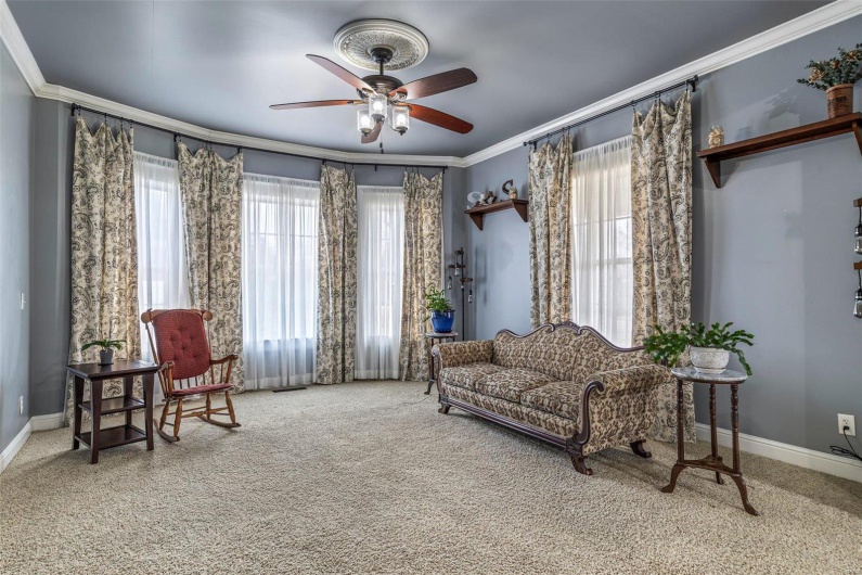 Living area with crown molding, ceiling fan, and carpet flooring