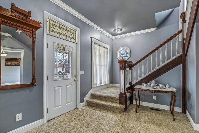 Carpeted foyer entrance with crown molding