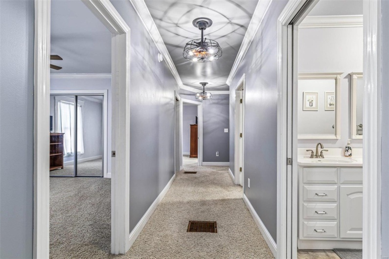 Corridor with sink, crown molding, and light colored carpet