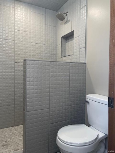 Bathroom featuring tiled shower and toilet