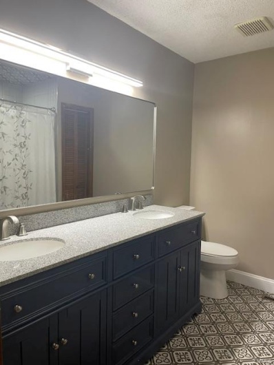 Bathroom featuring vanity, tile patterned flooring, toilet, and a textured ceiling