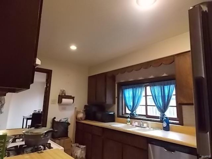 Kitchen with dark brown cabinets, sink, and stainless steel dishwasher