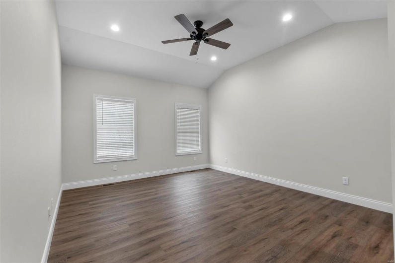 Empty room with ceiling fan, dark wood-type flooring, and lofted ceiling