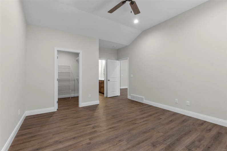 Unfurnished bedroom featuring a closet, a spacious closet, dark wood-type flooring, ceiling fan, and vaulted ceiling