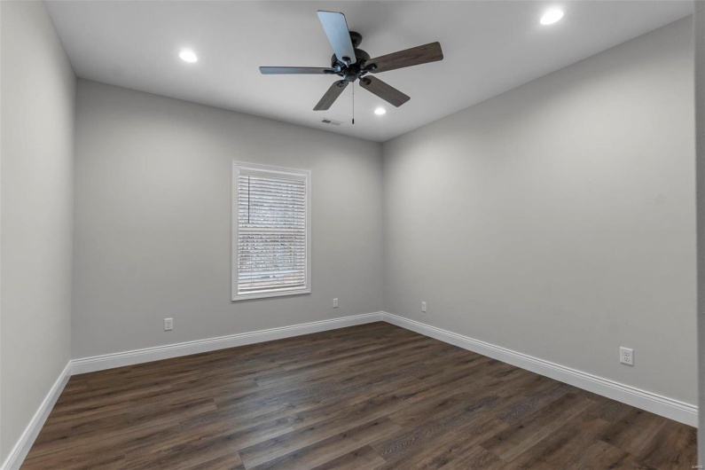 Unfurnished room featuring dark wood-type flooring and ceiling fan