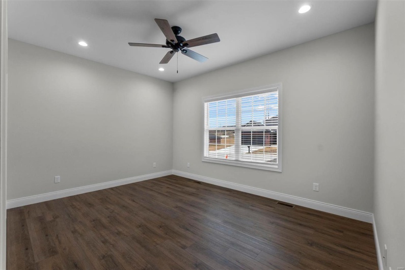 Spare room featuring dark wood-type flooring and ceiling fan