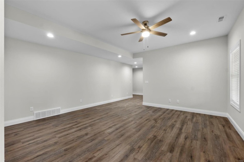 Empty room featuring ceiling fan and dark hardwood / wood-style flooring