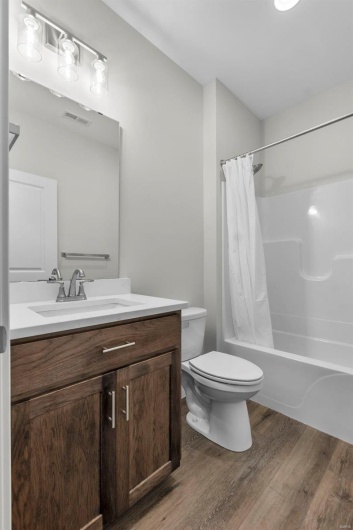 Full bathroom featuring hardwood / wood-style floors, vanity, toilet, and shower / bath combination with curtain