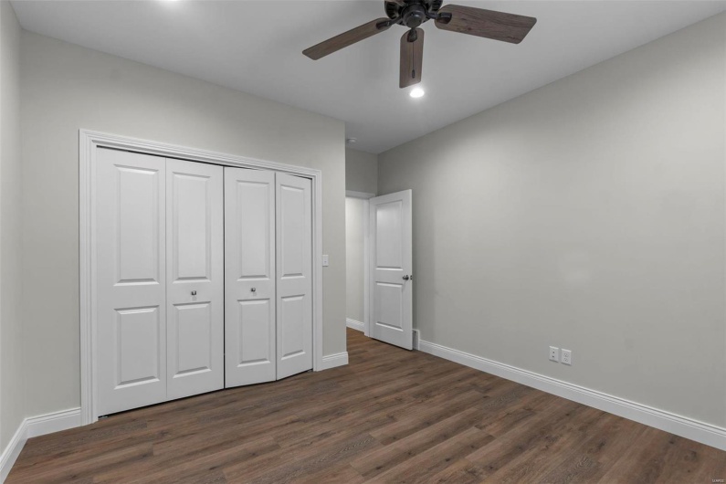 Unfurnished bedroom with ceiling fan, a closet, and dark wood-type flooring