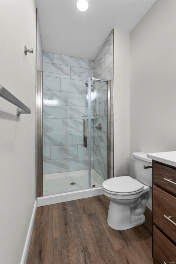 Bathroom with hardwood / wood-style flooring, vanity, toilet, and a shower with door