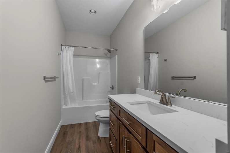 Full bathroom with toilet, hardwood / wood-style flooring, shower / bathtub combination with curtain, and vanity