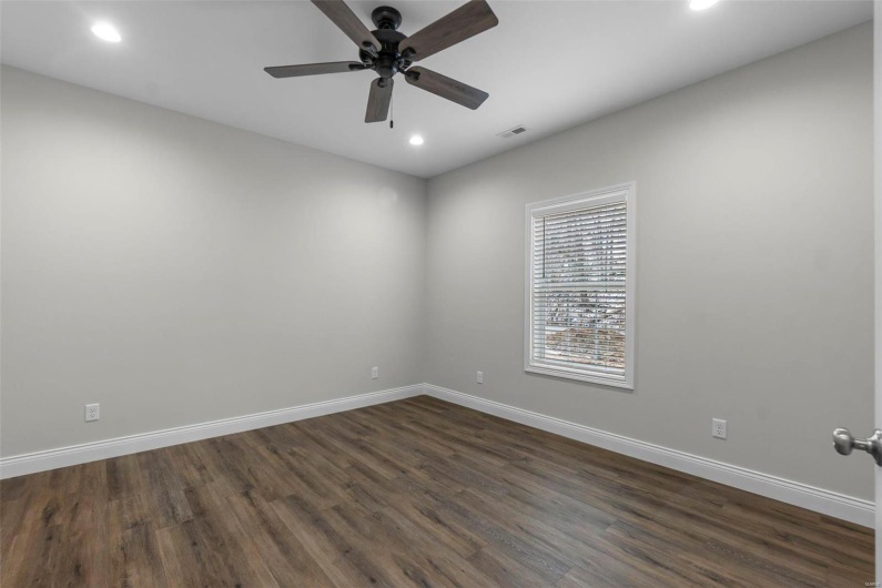 Empty room with ceiling fan and dark hardwood / wood-style flooring