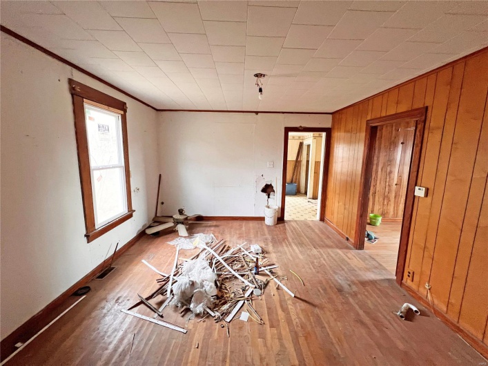 Spare room with crown molding, wood walls, and light wood-type flooring