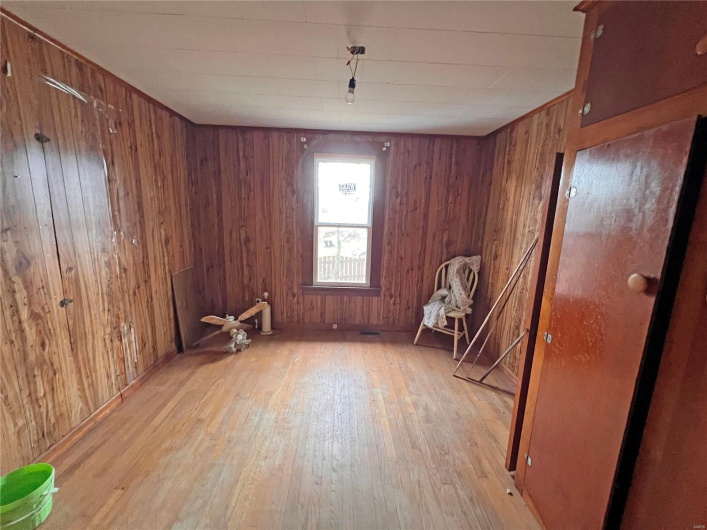 Empty room with light hardwood / wood-style floors and wood walls